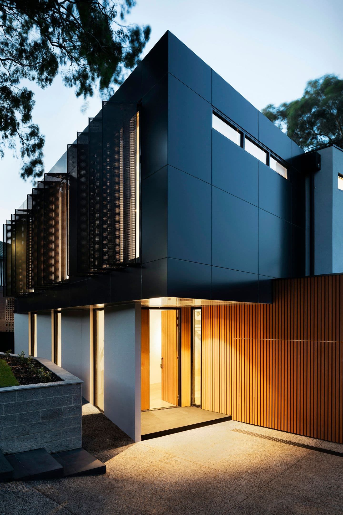 Modern black timber residence glowing at dusk