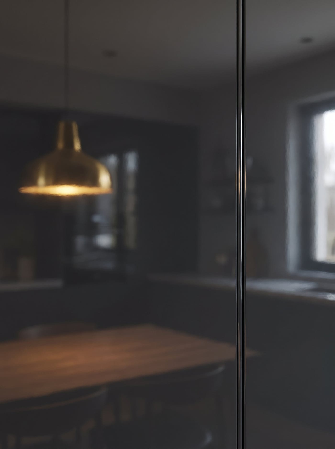 High-gloss charcoal lacquered cabinet door reflecting a brass pendant